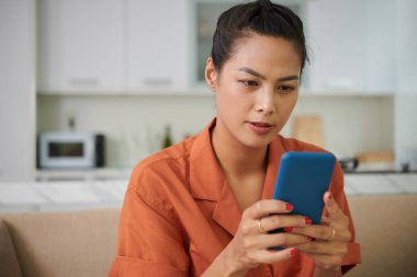 Ciddi bir genç kadının portresi akıllı telefondan mesaj veya tebligat okuyor.