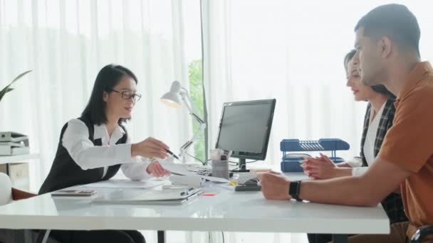 アジアの女性保険代理店のウエストアップオフィスミーティングを持ちながら若い夫婦のクライアントをコンサルティング — ストック動画
