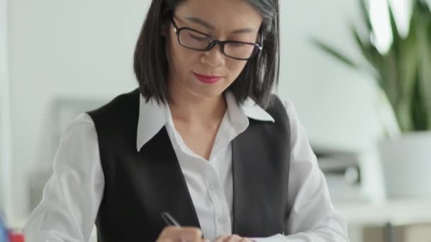 事務所で書類作成中に契約書にスタンプを押すアジアの女性Olのダウンショットを傾ける — ストック動画
