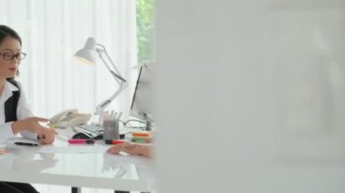 Orta yaşlı Asyalı kadının modern ofisteki genç kadın banka temsilcisine danışmanlık yaptığı bir fotoğraf.