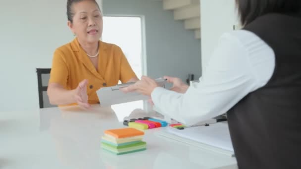 古いアジアの女性のウエストアップ彼女を助けるエージェントとオフィスミーティングを持っている間 保険契約に署名 — ストック動画