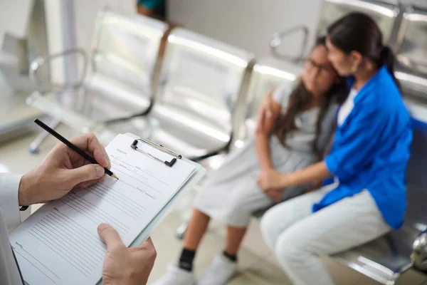 Lekarz Wypełnianie Karty Medycznej Podczas Rozmowy Matką Nastolatki Dziewczyny — Zdjęcie stockowe