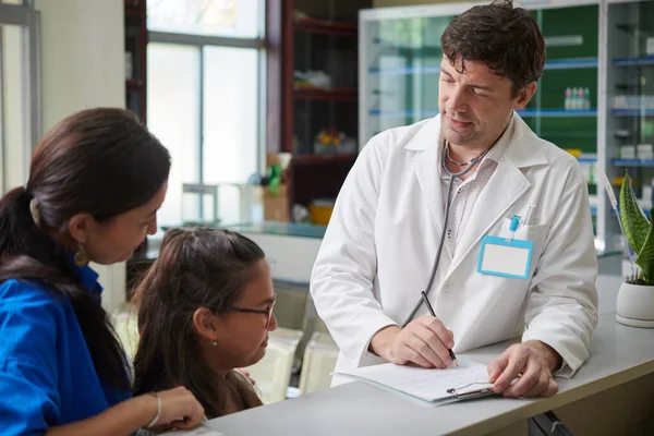 Çocuk Doktoru Reşit Olmayan Bir Kızla Konuşurken Sağlık Kartını Dolduruyor — Stok fotoğraf