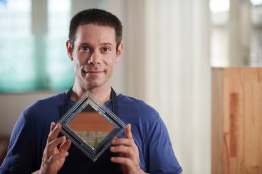 Gururlu cam işçisi ahşap çerçevede küçük bir ayna gösteriyor