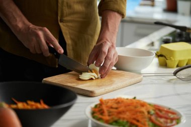Akşam yemeği için salata pişirirken haşlanmış yumurta kesen adam.