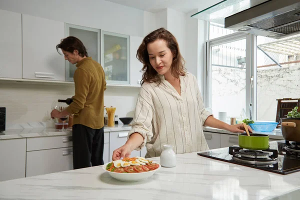 Kadın Kocası Şarap Koyarken Mutfak Masasına Salata Koyuyor — Stok fotoğraf