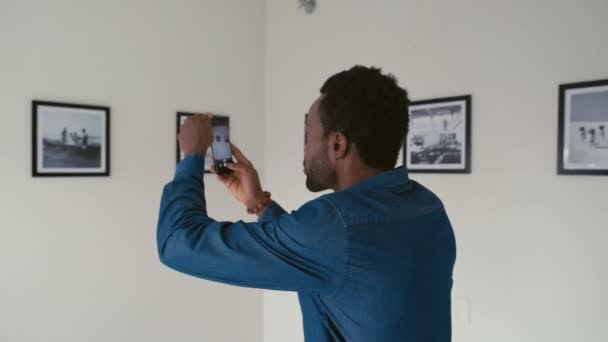 Młody Czarny Mężczyzna Robi Zdjęcia Smartfonem Wystawy Fotograficznej Galerii Sztuki — Wideo stockowe