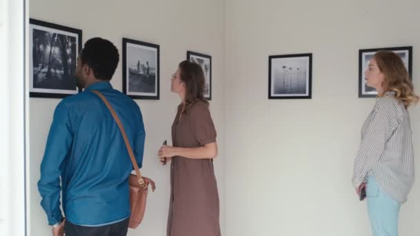 Keskipitkän Matkan Kävijöitä Katsomassa Valokuvanäyttelyä Taidegalleriassa Yksi Tyttö Ottaa Kuvia — kuvapankkivideo