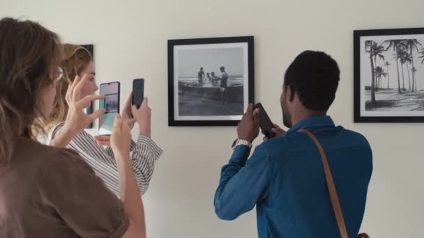Ομάδα Επισκεπτών Που Φωτογραφίζουν Κορνιζαρισμένη Φωτογραφία Στον Τοίχο Ενώ Επισκέπτονται — Αρχείο Βίντεο