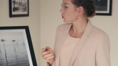 Dijital tablet kullanan ve resim sergisi için sanat eserlerini seçerken iş arkadaşıyla konuşan kadın galeri müdürü