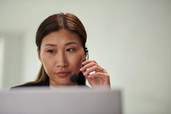 Arkadaşı Müşteriyle Konuşurken Kulaklık Takan Ciddi Bir Kadınının Portresi — Stok fotoğraf