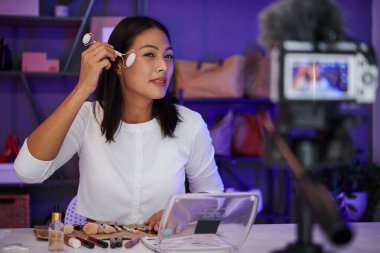 Gülümseyen kadın kuvars silindiriyle yüz masajı yaparken kendini filme alıyor.