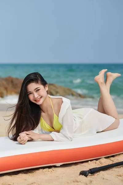 笑顔の若い女性は海で泳いだ後 パドルボードに横たわっています — ストック写真