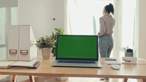 Közepes Felvételű Laptop Zöld Krómkulcsos Képernyővel Asztalon Beszél Telefonon Ablakról — Stock videók