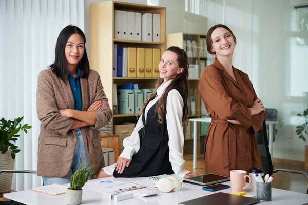 Portrait of successful business team of women smiling at camera standing in office