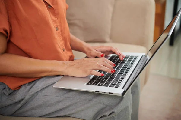 年轻女子坐在客厅沙发上在笔记本电脑上上网的特写镜头 — 图库照片