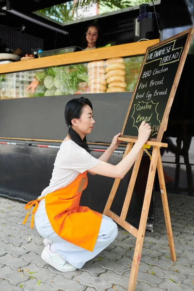 Vista Lateral Jovem Mulher Avental Laranja Escrevendo Menu Fast Food — Fotografia de Stock