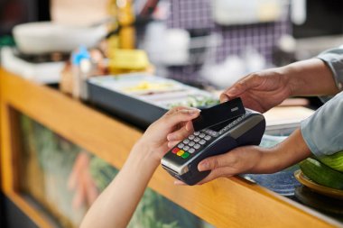 Kamyonette pişirilip satılan sokak yemekleri için ödeme sırasında kredi kartı ve tedarikçisi olan genç bayan müşterilerin elleri