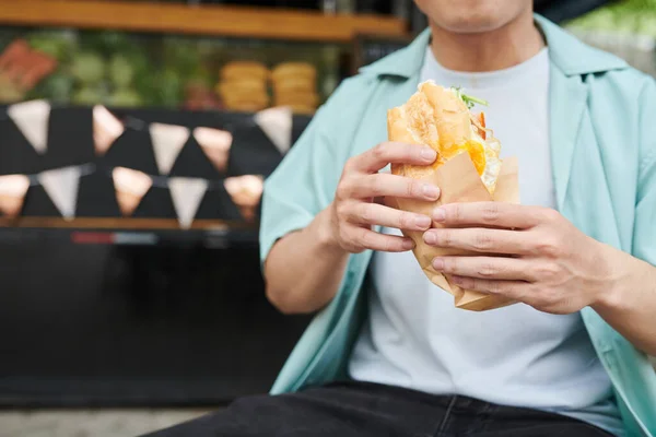 Zbliżenie Młody Głodny Człowiek Casualwear Trzymając Apetyczny Hot Dog Papier — Zdjęcie stockowe