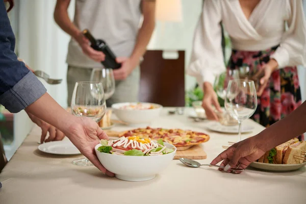 年轻朋友们在晚餐或家庭聚会上端着几碗开胃的自制沙拉和其他小吃时的特写镜头 — 图库照片