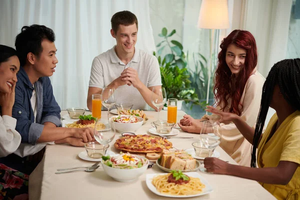 スマートカジュアルチャットでの若い異文化間の人々のグループは テーブルを提供し 自家製食品で構成されるディナーを楽しむ — ストック写真
