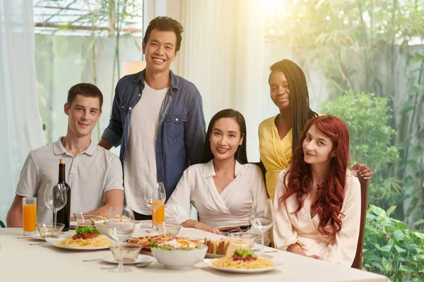 五位快乐的跨文化朋友坐在餐桌旁 准备着各种开胃的自制菜式 准备庆祝 — 图库照片