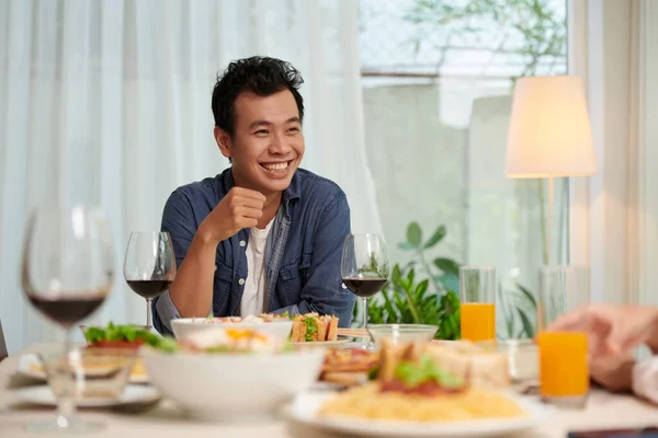 Günlük Giysili Neşeli Asyalı Genç Adam Yemek Masasında Oturmuş Konuklar — Stok fotoğraf