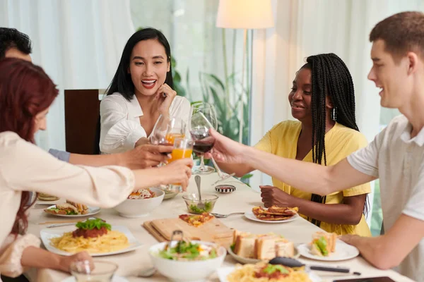テーブル席に座りながら赤ワインのワインを飲みながら 幸せな異文化間の友人のグループと一緒にホームパーティーを楽しむ — ストック写真