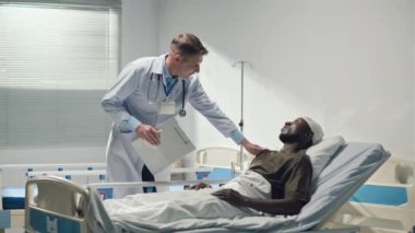 Afrikalı Amerikalı yaralı asker askeri hastanede doktor tarafından verilen sağlık belgesini imzalıyor.