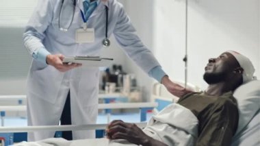 Kafasında kanama olan Afrikalı Amerikalı askerlere destek veren ve sağlık sigortasına imzalaması için belge veren doktor.
