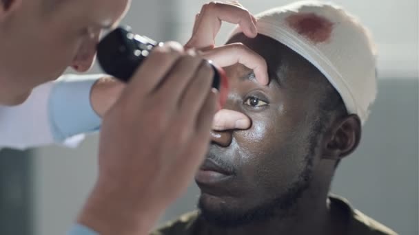 病院で頭部に傷を負った兵士の眼を調べるために懐中電灯を使用して医師のクローズアップ — ストック動画