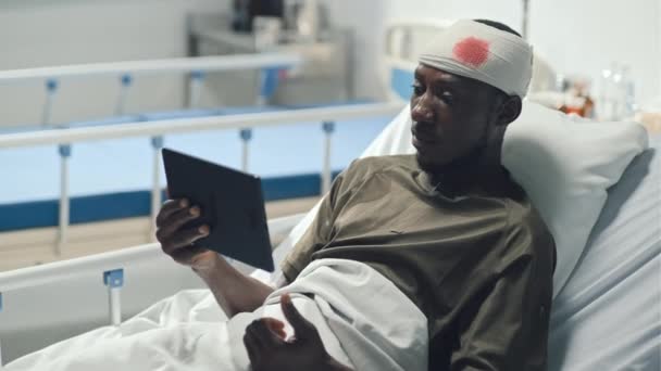 中镜头的非裔美国士兵头部受伤流血 通过视频电话与躺在医院病房床上的朋友交谈 — 图库视频影像