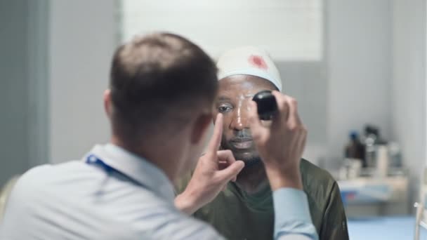 Médico Usando Linterna Para Comprobar Visión Pacientes Afroamericanos Heridos Hospital — Vídeos de Stock