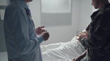 Beyaz üniformalı doktor ve asker hastanede yaralanan hastaların sağlık durumundan ve tedavisinden bahsediyorlar.