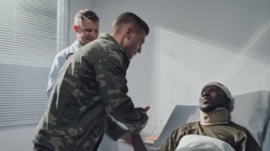 Üniformalı asker yaralı arkadaşını ziyaret ediyor ve askeri hastanede ona destek oluyor.