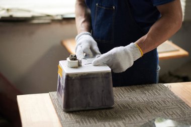 Cam işçisinin eldiven giyip atölyedeki iş aletleriyle cam kestiği yakın plan.