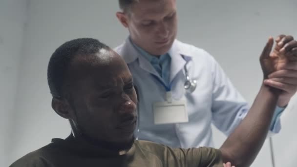 Lékař Uniformě Vyšetřuje Poraněnou Ruku Uzdraveného Pacienta Sedícího Nemocnici — Stock video
