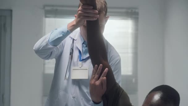 身穿白衣的医生检查躺在医院病房病床上的康复病人的受伤手臂 — 图库视频影像