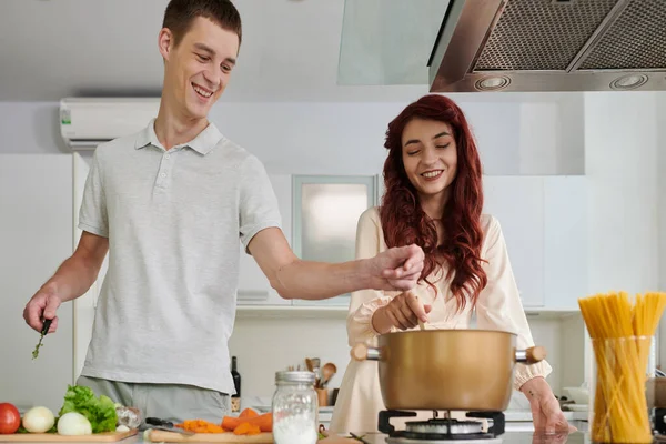 一对快乐的夫妇在平底锅里加些调料和煮沸的汤 — 图库照片
