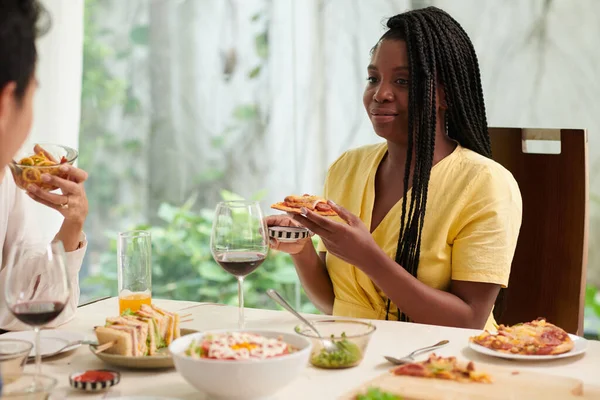 笑顔黒の若い女性は友人と夕食時に自家製ピザのスライスを楽しんで — ストック写真