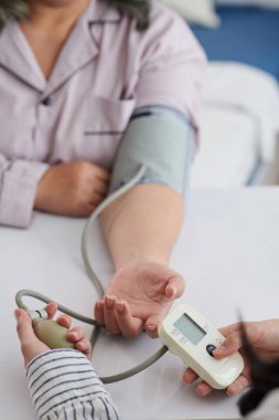 Kızının eve geldiğinde tansiyonunu ölçmesi için anneye yardım ettiği yakın plan.