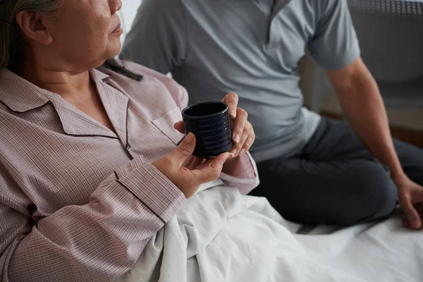 Starsza Kobieta Pije Herbatę Łóżku Rozmawia Mężem — Zdjęcie stockowe
