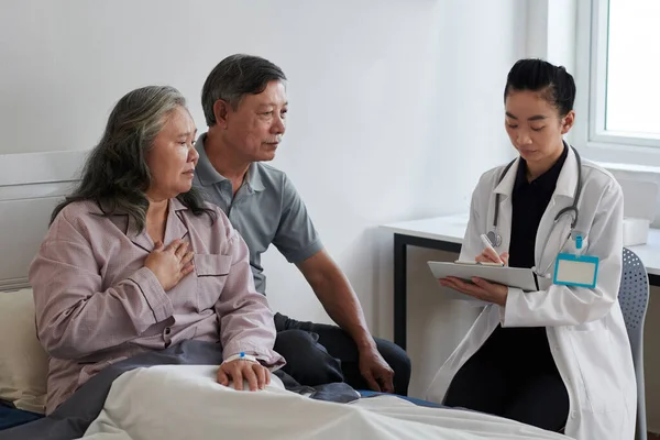 Allmänpraktiserande Läkare Antecknar När Han Pratar Med Sjuk Äldre Kvinna — Stockfoto