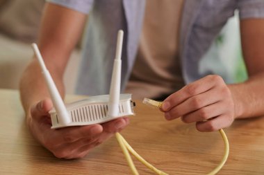 Wi-fi yönlendiricisine ethernet kablosu takan adamın elleri
