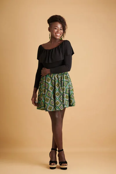 黒のフリルの上に緑のスカートを身に着けている幸せな若い笑顔の女性と幾何学模様とヒールサンダル — ストック写真