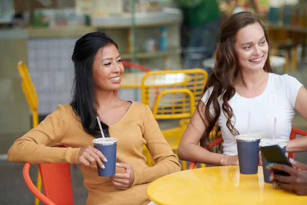 Smiling Young Women Sitting Cafe Table Drinking Iced Tea Listening — Stock Photo, Image
