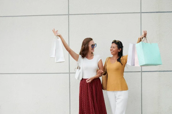 Glücklich Lächelnde Freunde Heben Die Hände Mit Einkaufstüten Und Schauen — Stockfoto