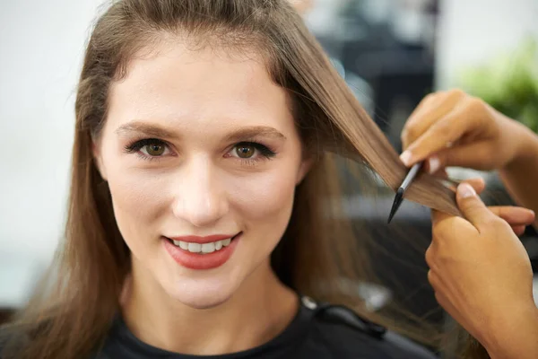 Gülümseyen Genç Bir Kadın Kuaför Saçlarını Tararken Tararken Kameraya Bakıyor — Stok fotoğraf