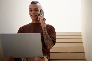 Mutlu genç yazılım geliştiricisi telefonda meslektaşlarına heyecan verici haberler veriyor.