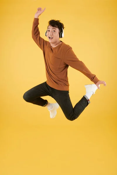 Jonge Aziatische Man Hoofdtelefoon Springen Lucht Tegen Gele Achtergrond — Stockfoto